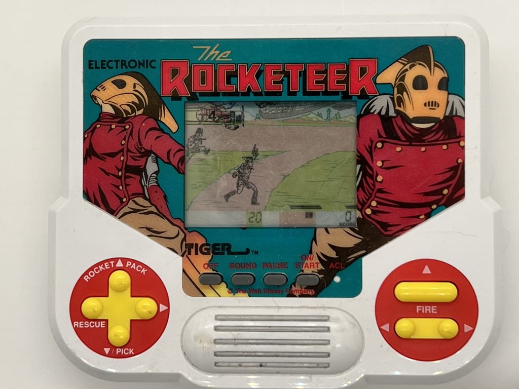An electronic video game of The Rocketeer. The screen shows The Rocketeer firing a gun upwards while a Nazi soldier jumps onto screen.