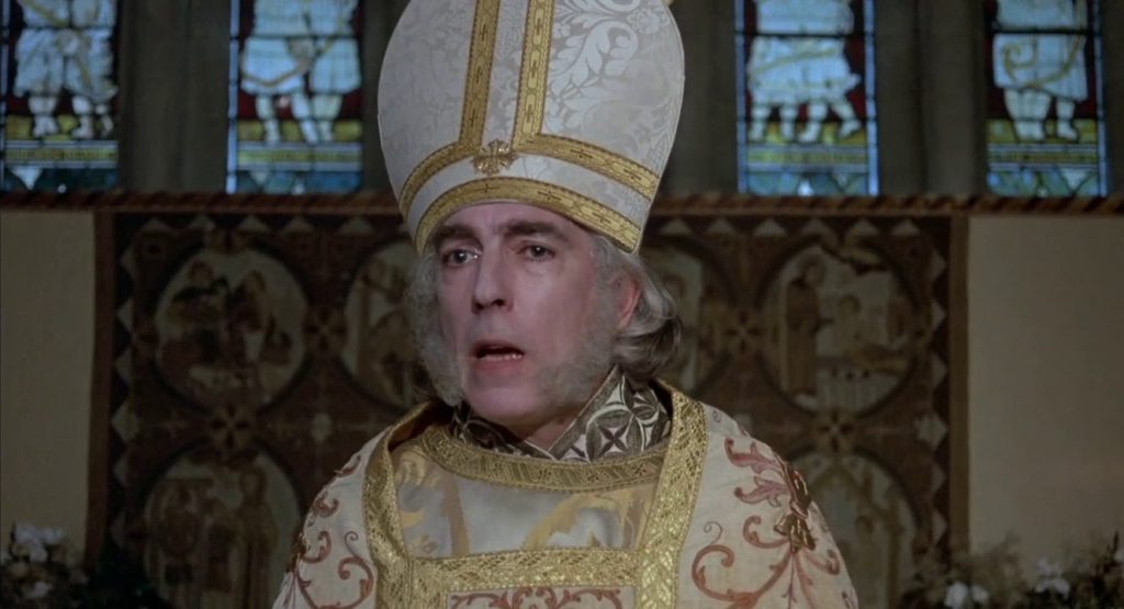 A clergyman in ornate gold-and-white vestments. He has big muttonchops and a confused expression.